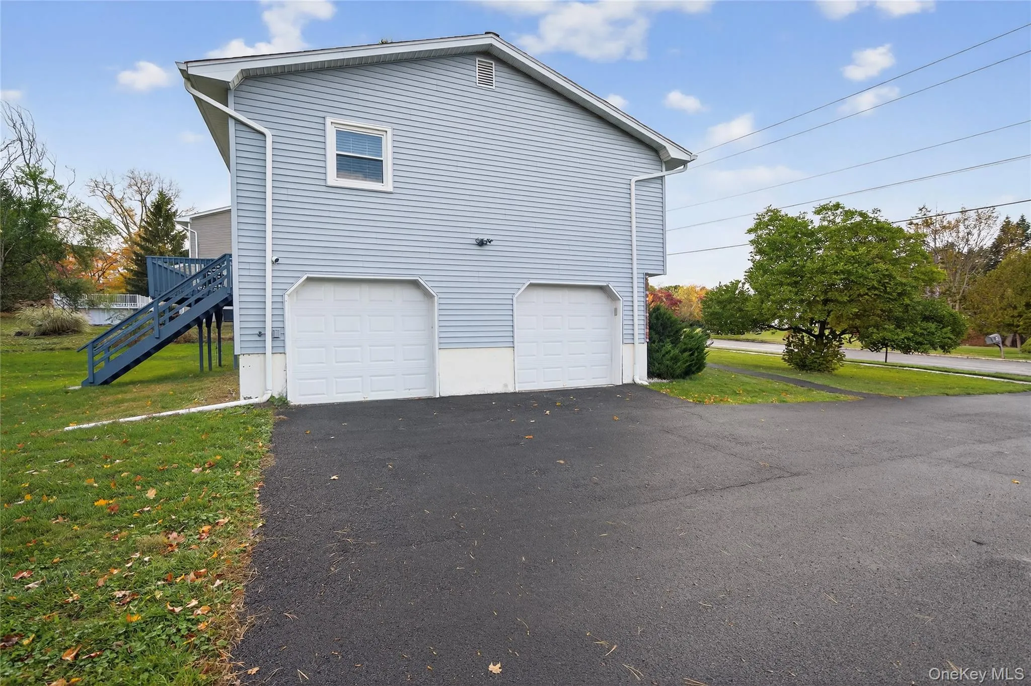 View of side of home with stairway, asphalt driveway, a yard, and an attached garage View of side of home with stairway, asphalt driveway, a yard, and an attached garage