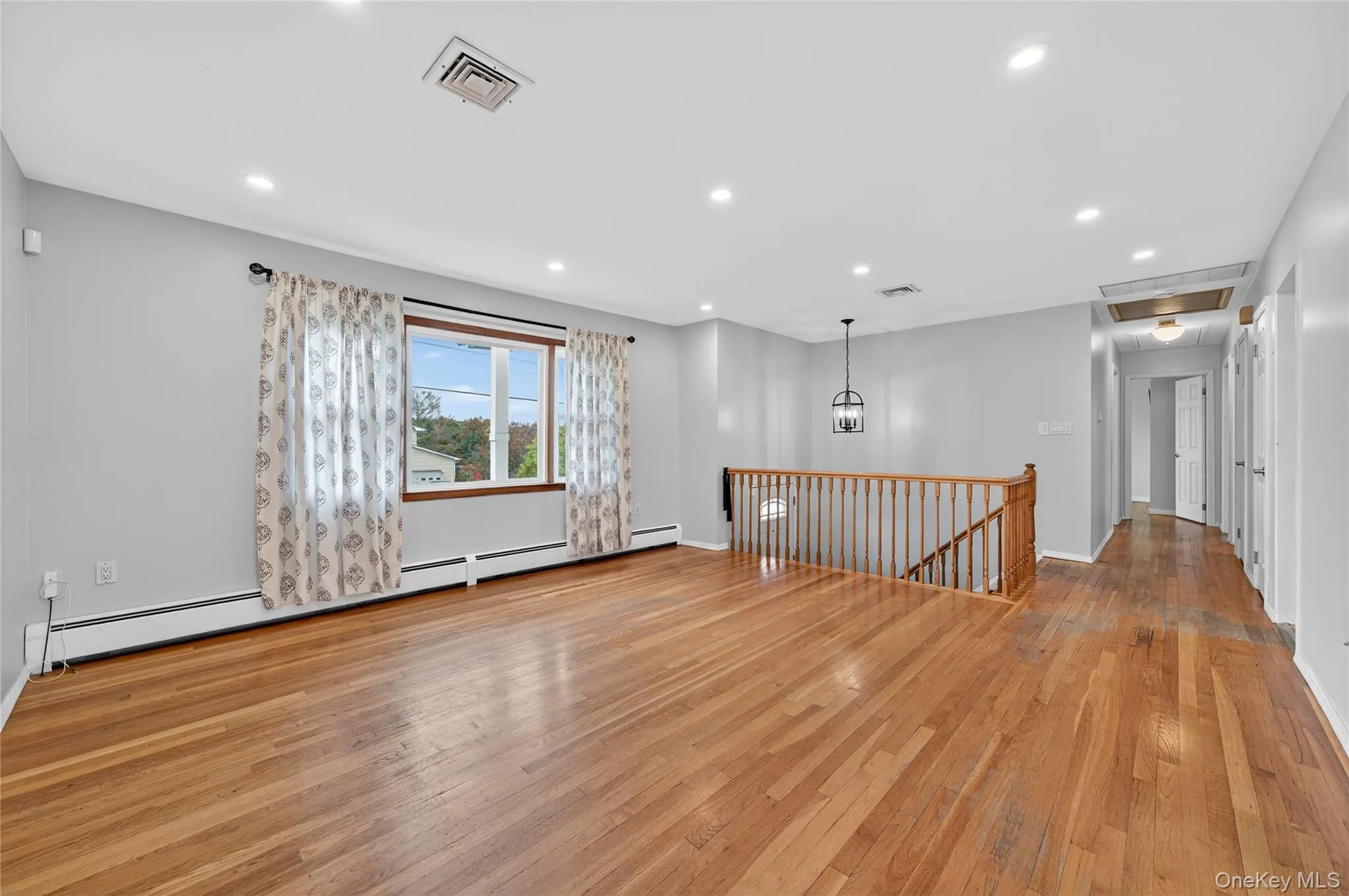 Unfurnished room with recessed lighting, light wood finished floors, attic access, and a baseboard radiator Unfurnished room with recessed lighting, light wood finished floors, attic access, and a baseboard radiator