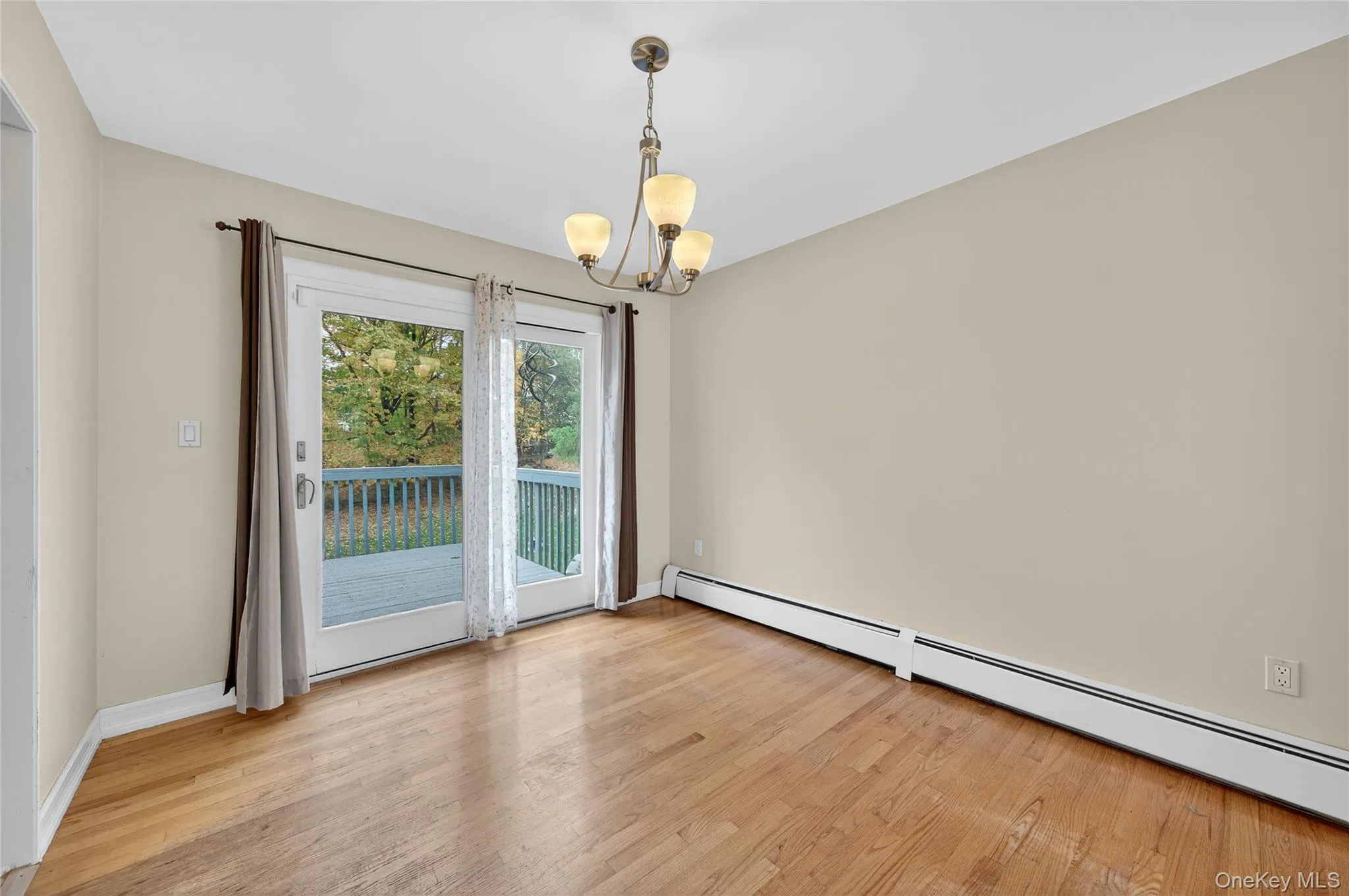 Spare room with a baseboard heating unit, light wood-style floors, and a chandelier Spare room with a baseboard heating unit, light wood-style floors, and a chandelier