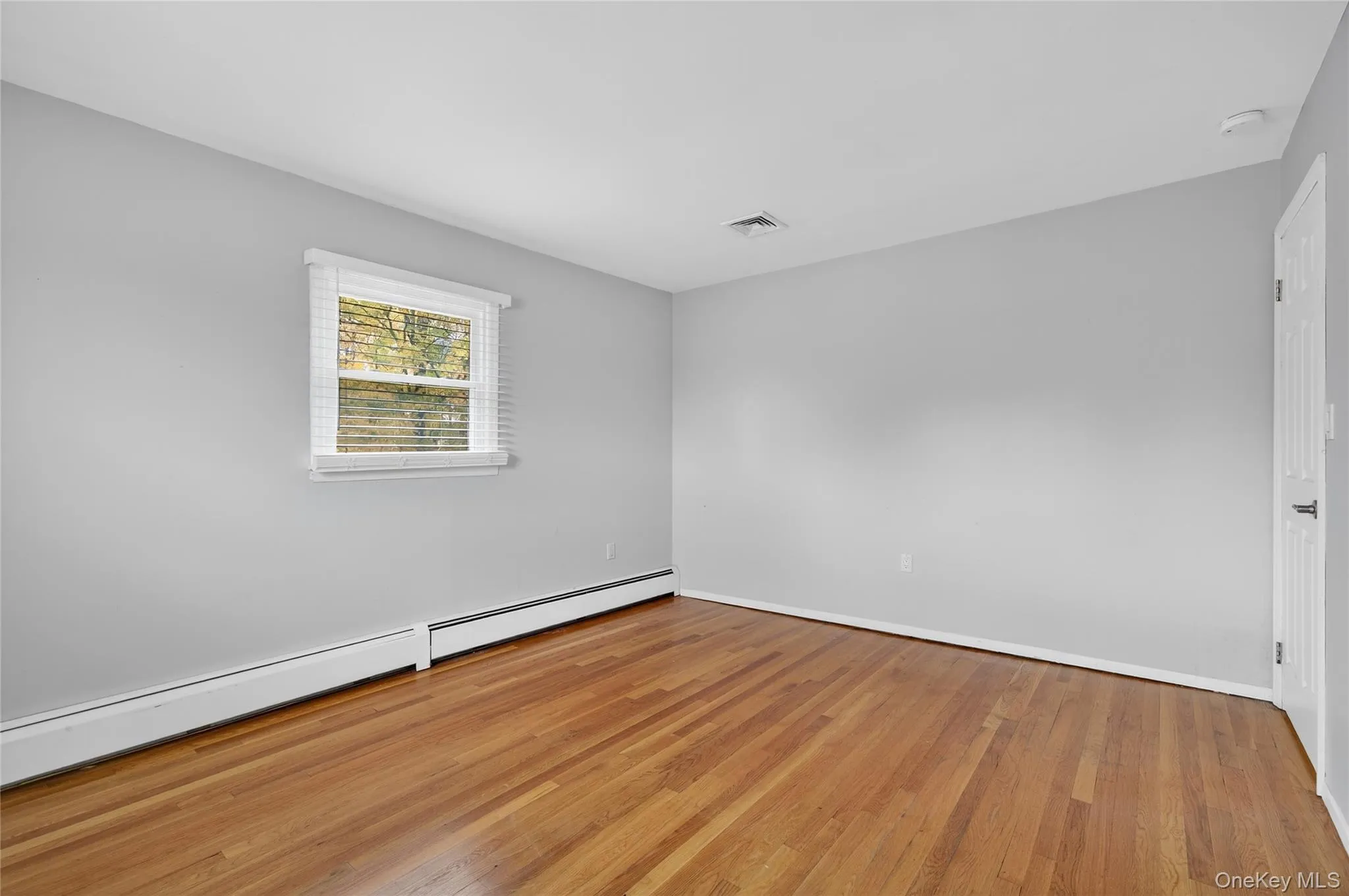 Spare room with a baseboard heating unit and light wood-style floors Spare room with a baseboard heating unit and light wood-style floors