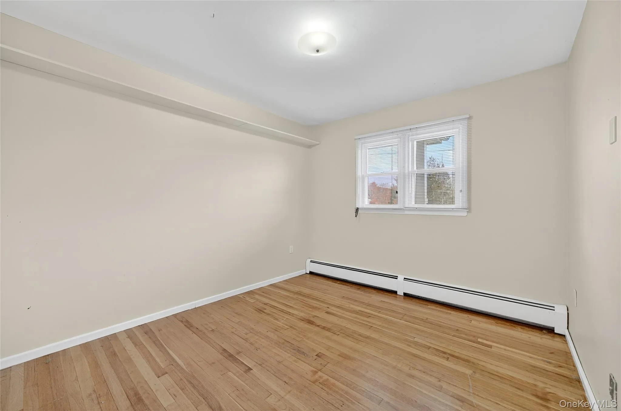 Unfurnished room featuring a baseboard heating unit and light wood-style floors Unfurnished room featuring a baseboard heating unit and light wood-style floors