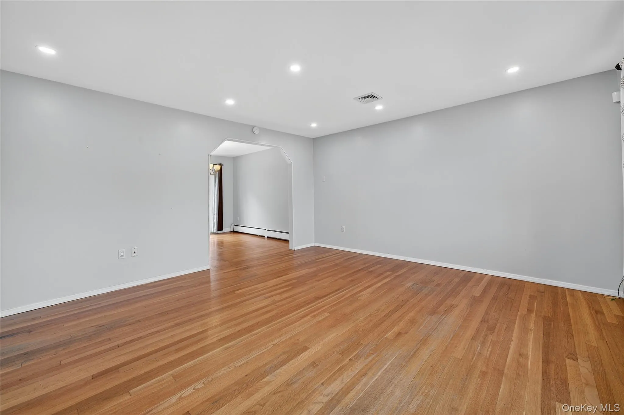 Spare room featuring arched walkways, recessed lighting, light wood finished floors, and a baseboard heating unit Spare room featuring arched walkways, recessed lighting, light wood finished floors, and a baseboard heating unit