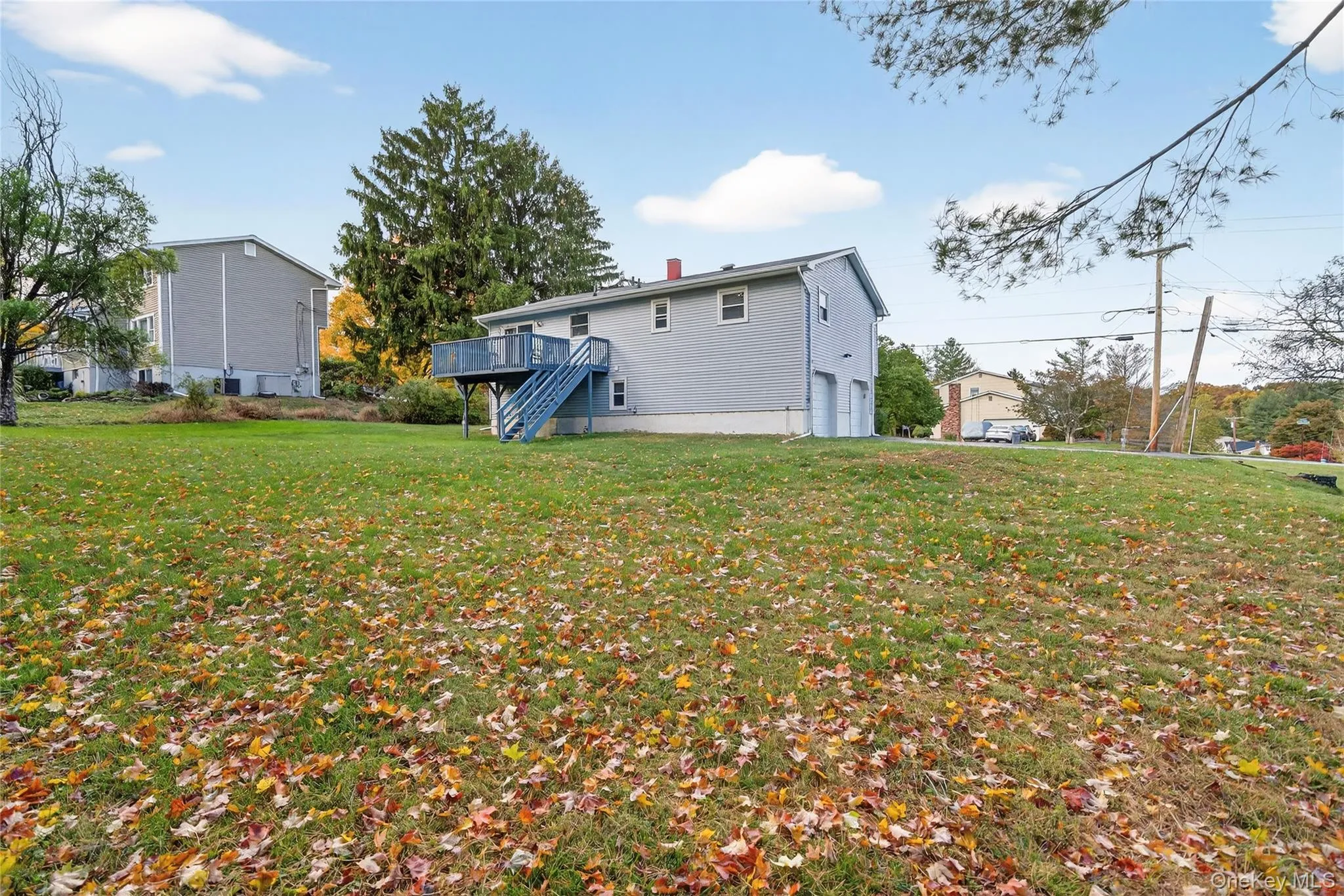 Rear view of property with a lawn, stairs, a garage, a wooden deck, and a chimney Rear view of property with a lawn, stairs, a garage, a wooden deck, and a chimney