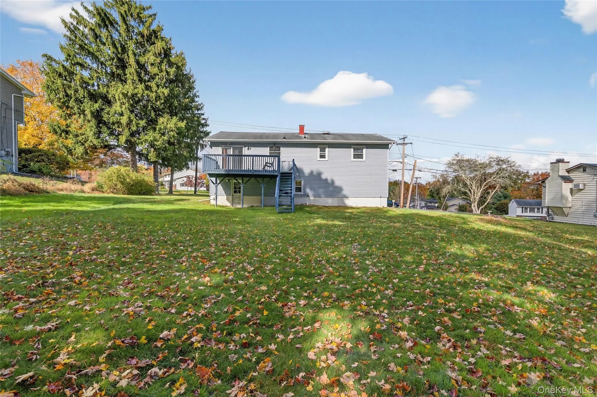 Rear view of property with a lawn, a wooden deck, and stairway Rear view of property with a lawn, a wooden deck, and stairway