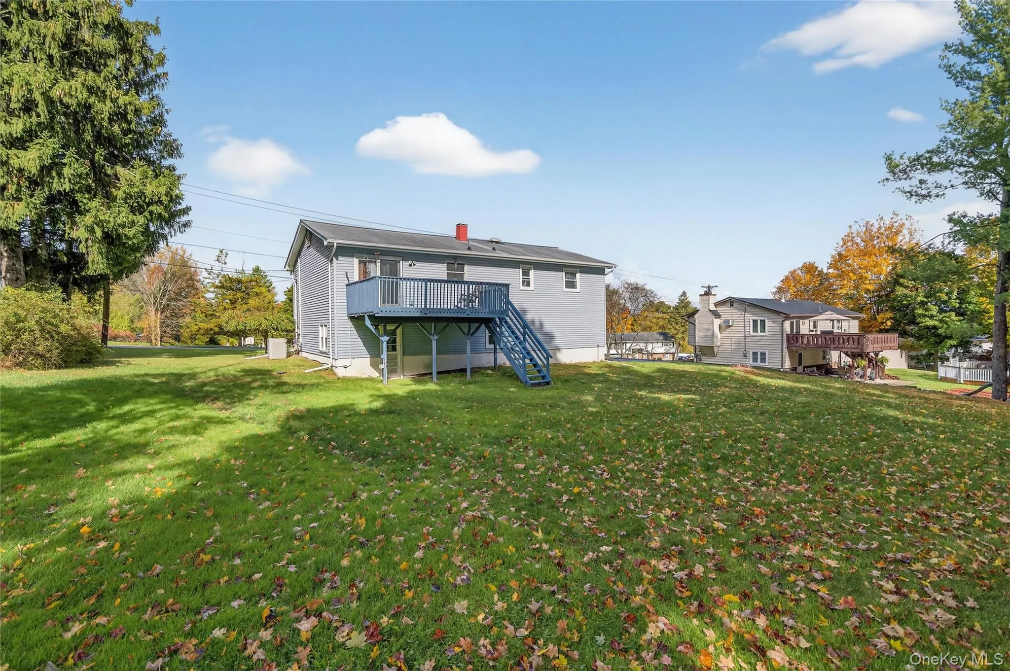 Back of property featuring a wooden deck, stairway, a yard, and a chimney Back of property featuring a wooden deck, stairway, a yard, and a chimney
