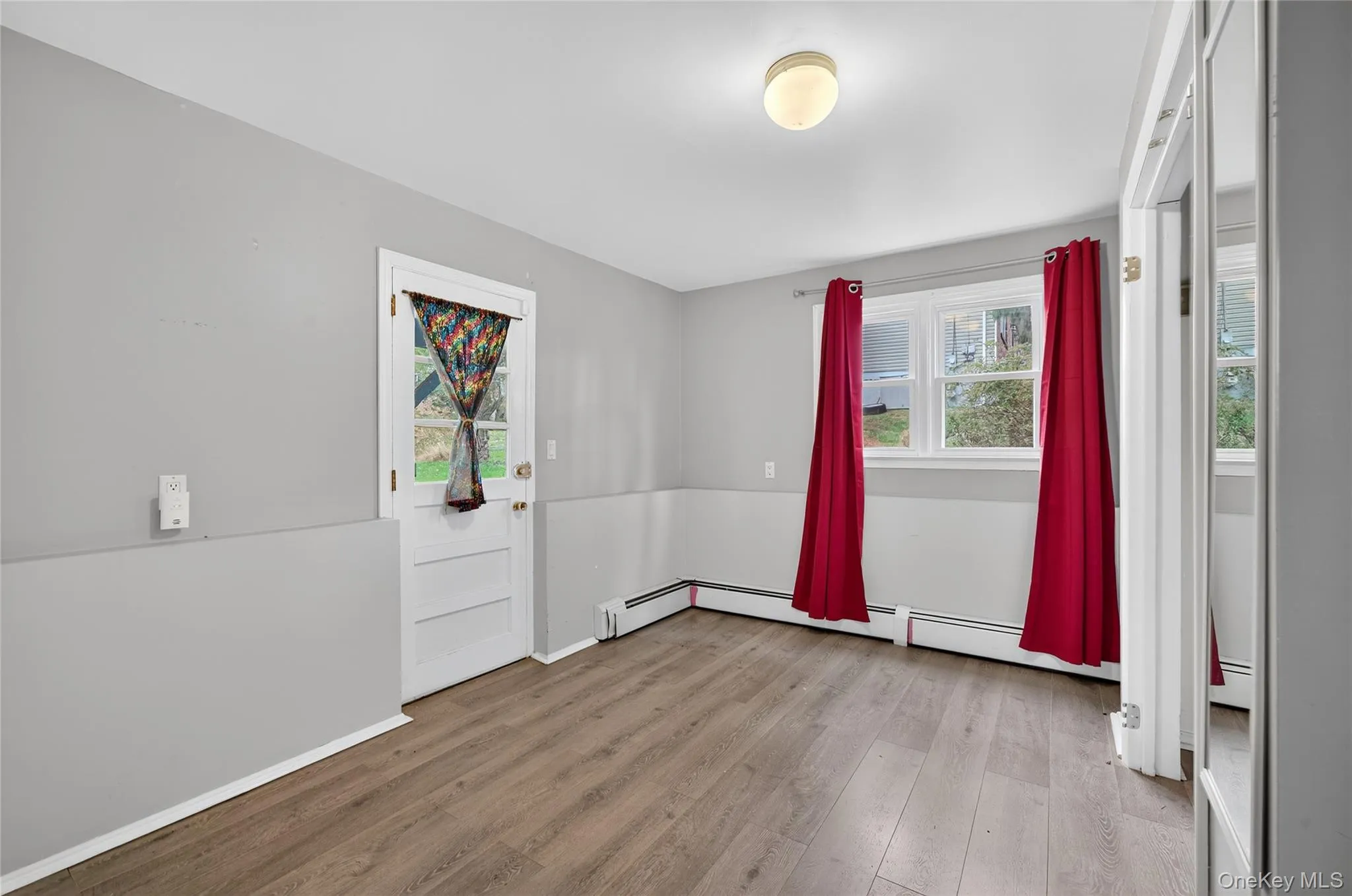 Spare room with light wood-style floors, healthy amount of natural light, and a baseboard heating unit Spare room with light wood-style floors, healthy amount of natural light, and a baseboard heating unit