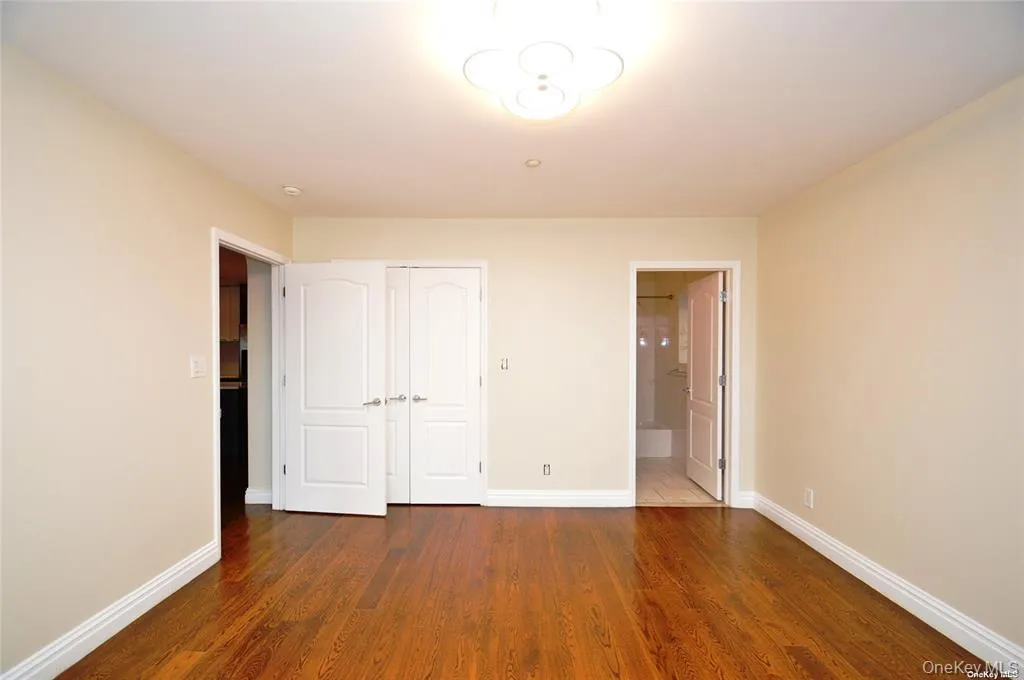 Unfurnished bedroom featuring dark wood-style floors, a closet, and connected bathroom Unfurnished bedroom featuring dark wood-style floors, a closet, and connected bathroom