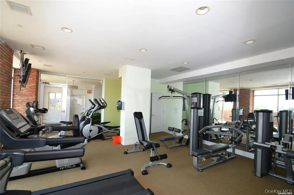 Exercise room with floor to ceiling windows, brick wall, and recessed lighting Exercise room with floor to ceiling windows, brick wall, and recessed lighting