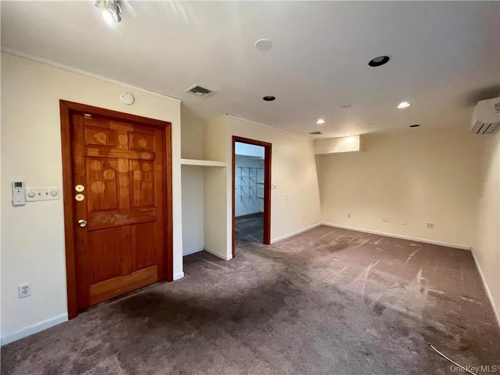 Spare room with dark colored carpet, recessed lighting, and a wall mounted air conditioner Spare room with dark colored carpet, recessed lighting, and a wall mounted air conditioner