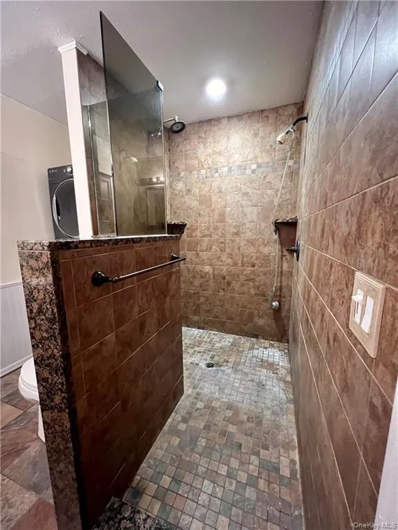 Full bathroom with a walk in shower, a wainscoted wall, and washer / clothes dryer Full bathroom with a walk in shower, a wainscoted wall, and washer / clothes dryer