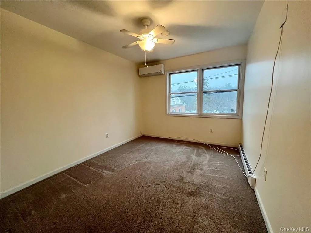 Carpeted spare room with ceiling fan, a wall unit AC, and baseboard heating Carpeted spare room with ceiling fan, a wall unit AC, and baseboard heating