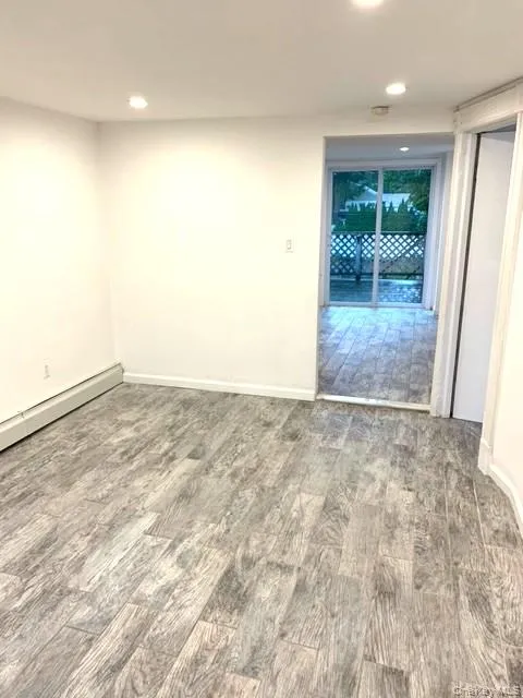 Spare room with wood finished floors, a baseboard radiator, and recessed lighting Spare room with wood finished floors, a baseboard radiator, and recessed lighting