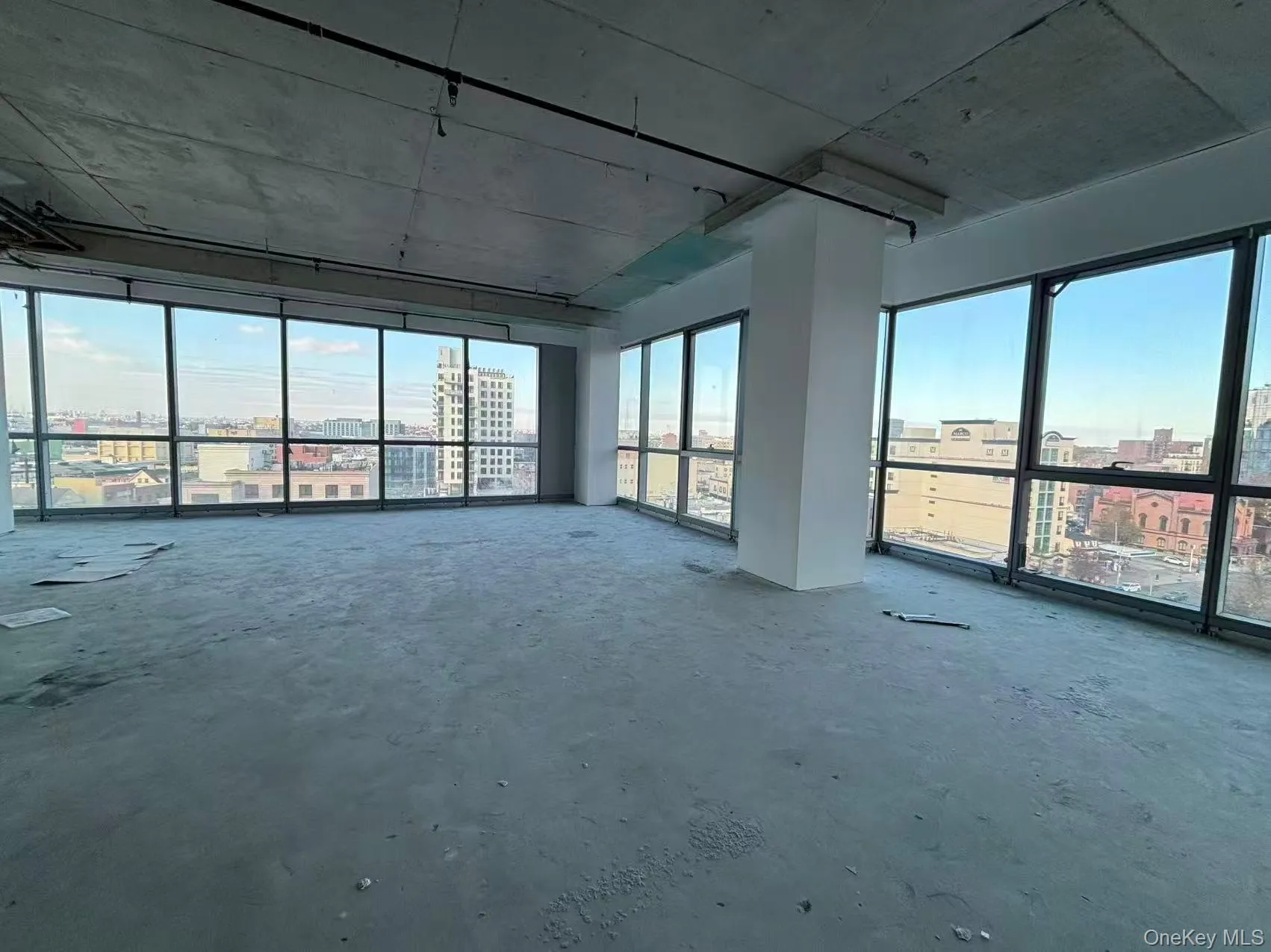 Empty room with healthy amount of natural light, a city view, and concrete floors Empty room with healthy amount of natural light, a city view, and concrete floors