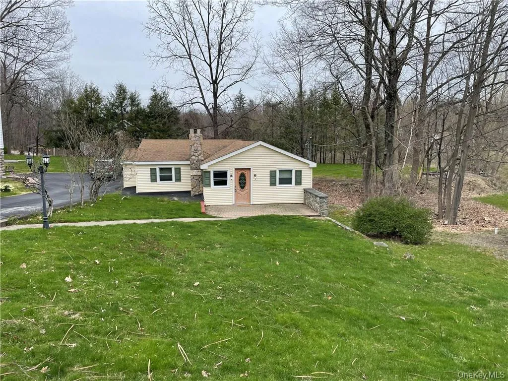 View of front of house with a front yard, a chimney, and a patio View of front of house with a front yard, a chimney, and a patio