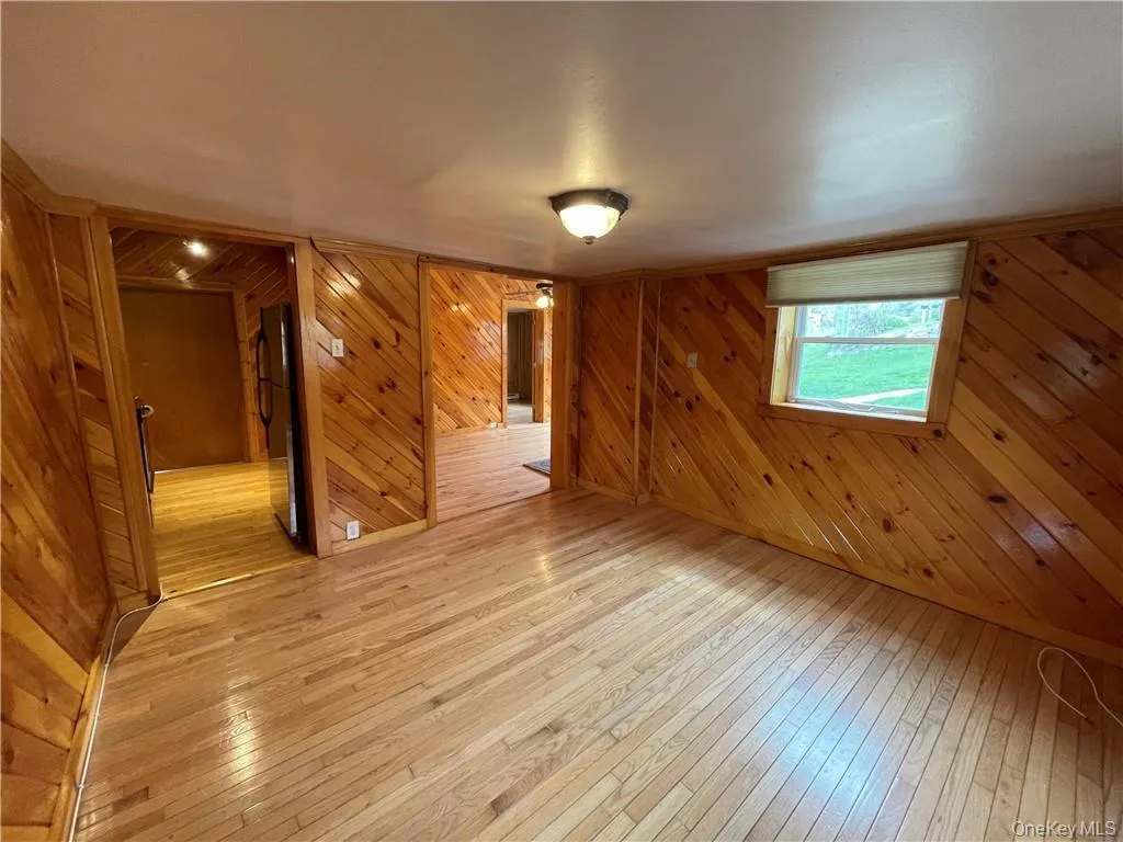 Spare room featuring light wood-type flooring and wood walls Spare room featuring light wood-type flooring and wood walls