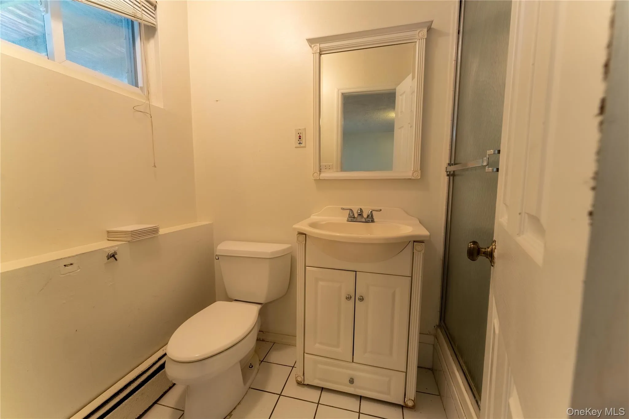 Bathroom featuring light tile patterned floors, a baseboard heating unit, a stall shower, and vanity Bathroom featuring light tile patterned floors, a baseboard heating unit, a stall shower, and vanity
