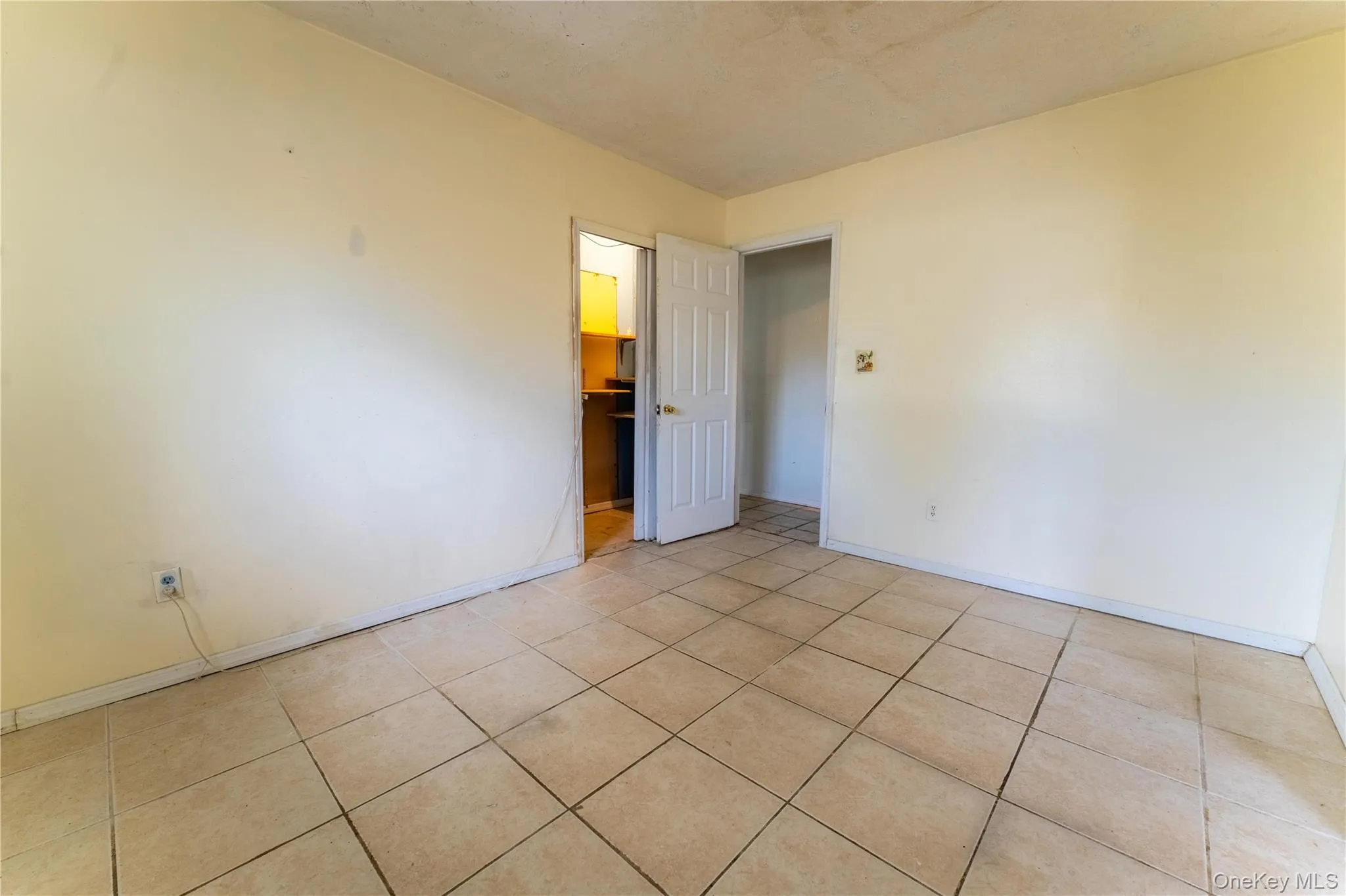Unfurnished bedroom featuring light tile patterned flooring and a spacious closet Unfurnished bedroom featuring light tile patterned flooring and a spacious closet