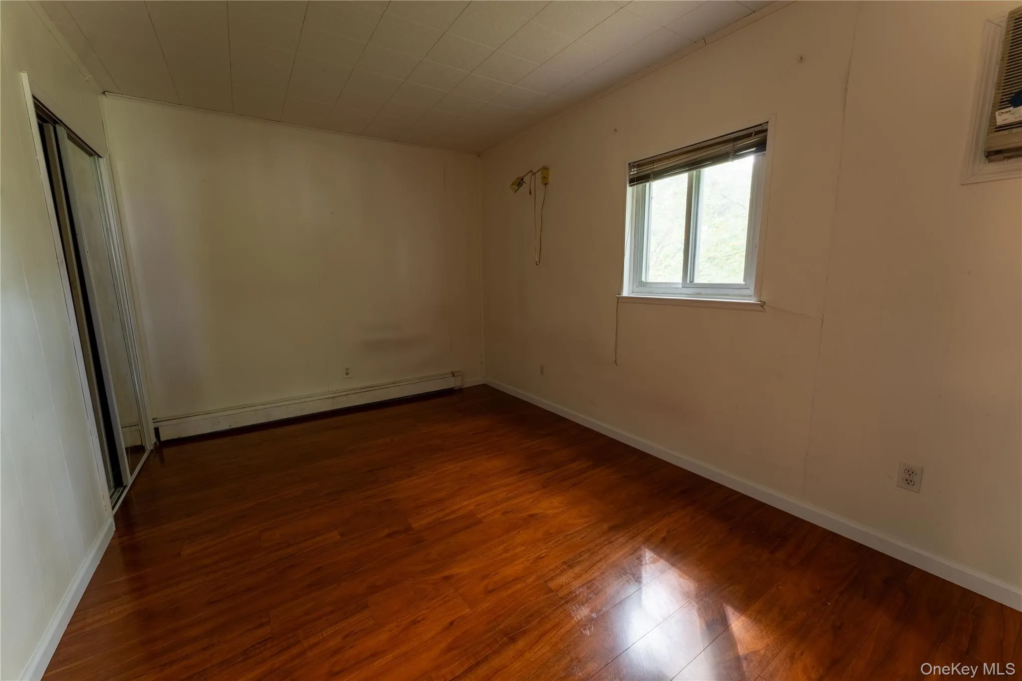 Empty room with dark wood-style floors and baseboard heating Empty room with dark wood-style floors and baseboard heating