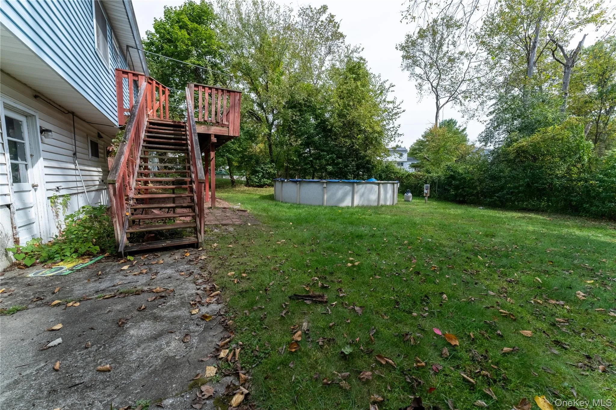 View of green lawn featuring stairway, a covered pool, and a deck View of green lawn featuring stairway, a covered pool, and a deck