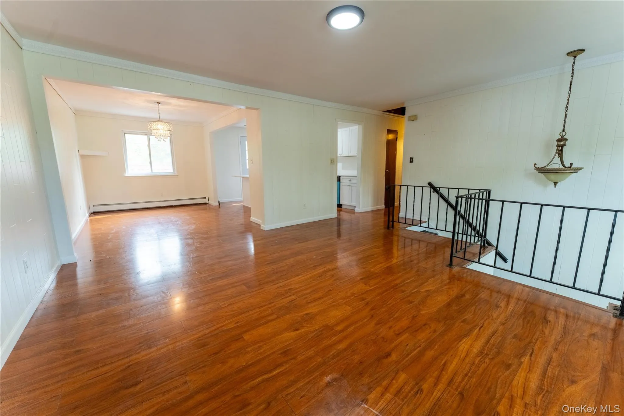 Spare room with crown molding, wood finished floors, a baseboard radiator, and a chandelier Spare room with crown molding, wood finished floors, a baseboard radiator, and a chandelier