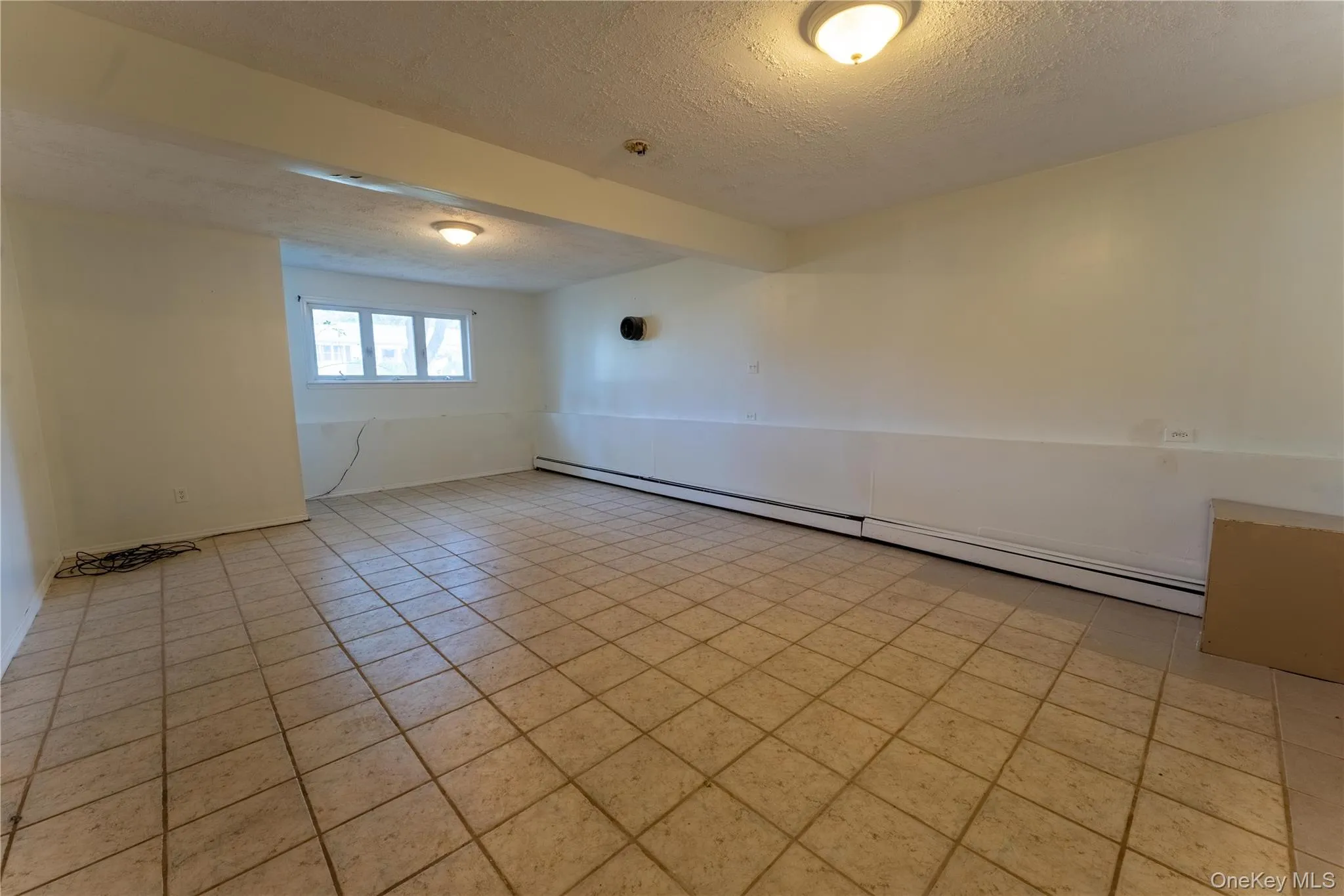 Spare room featuring a textured ceiling, a baseboard radiator, and light tile patterned floors Spare room featuring a textured ceiling, a baseboard radiator, and light tile patterned floors