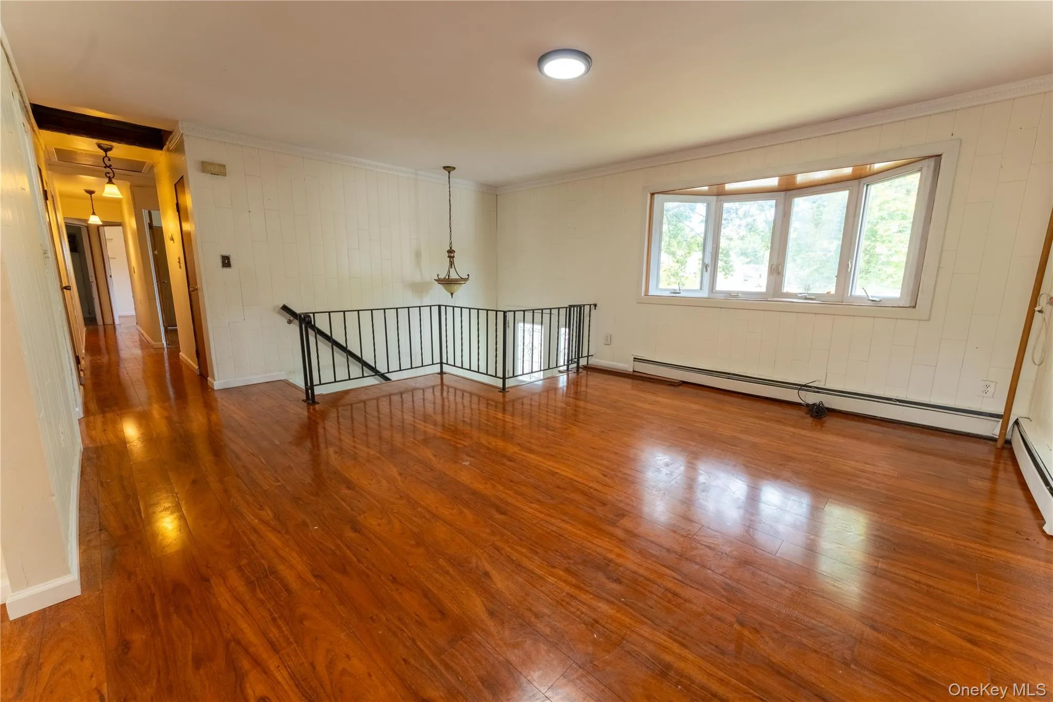 Unfurnished room with ornamental molding, wood finished floors, baseboard heating, and wood walls Unfurnished room with ornamental molding, wood finished floors, baseboard heating, and wood walls