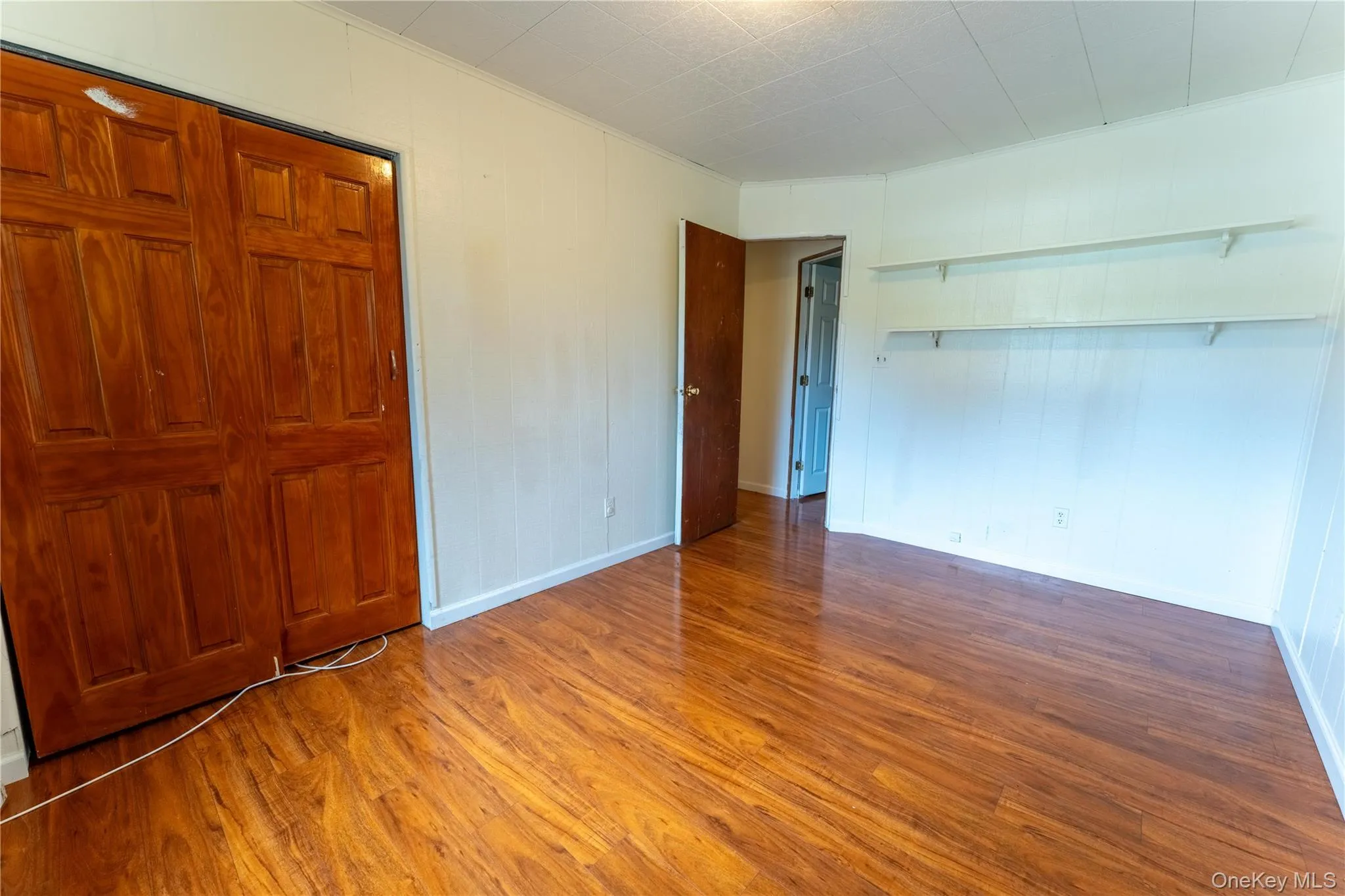 Unfurnished bedroom with dark wood-style flooring, a closet, and ornamental molding Unfurnished bedroom with dark wood-style flooring, a closet, and ornamental molding