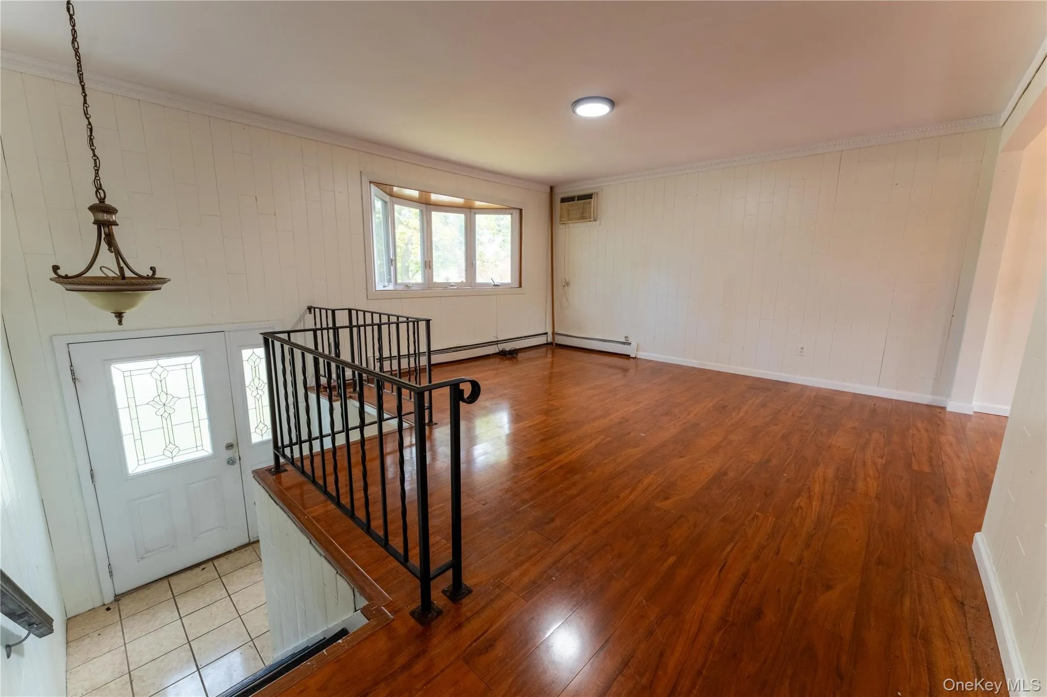 Entryway featuring wood finished floors, wood walls, ornamental molding, stairway, and a wall mounted AC Entryway featuring wood finished floors, wood walls, ornamental molding, stairway, and a wall mounted AC