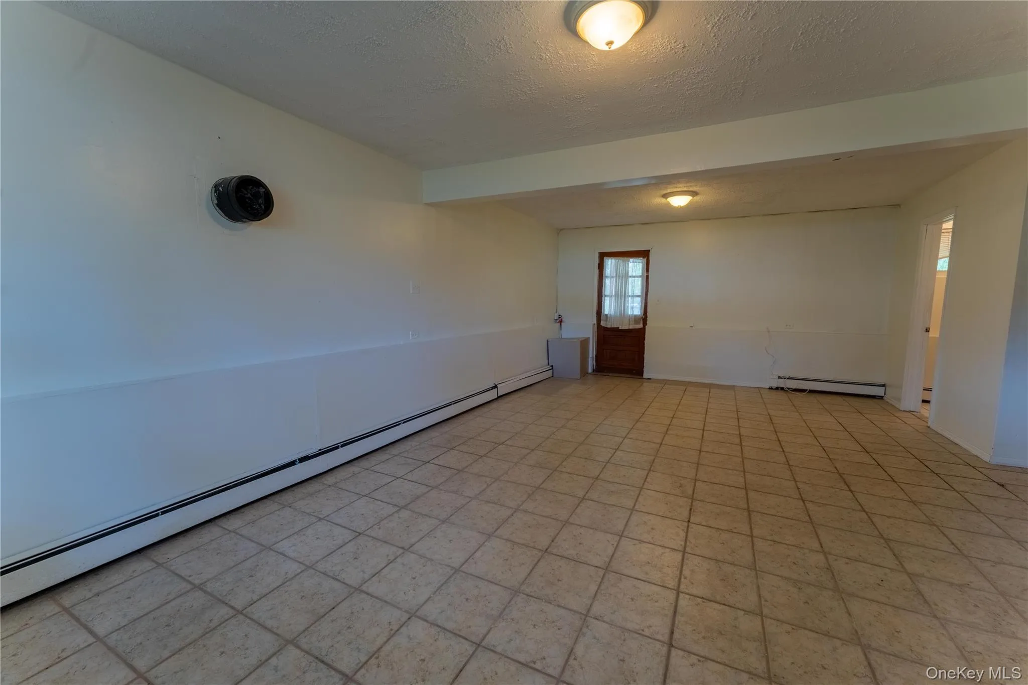 Unfurnished room featuring a baseboard radiator, a textured ceiling, and beamed ceiling Unfurnished room featuring a baseboard radiator, a textured ceiling, and beamed ceiling