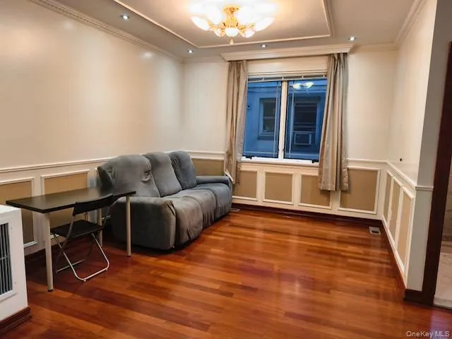 Sitting room featuring a decorative wall, a wainscoted wall, a chandelier, dark wood-style flooring, and crown molding Sitting room featuring a decorative wall, a wainscoted wall, a chandelier, dark wood-style flooring, and crown molding