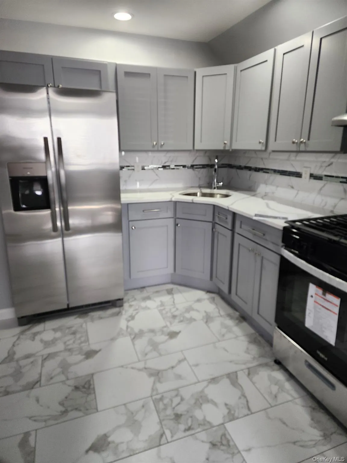 Kitchen with gray cabinetry, appliances with stainless steel finishes, and light marble finish flooring Kitchen with gray cabinetry, appliances with stainless steel finishes, and light marble finish flooring