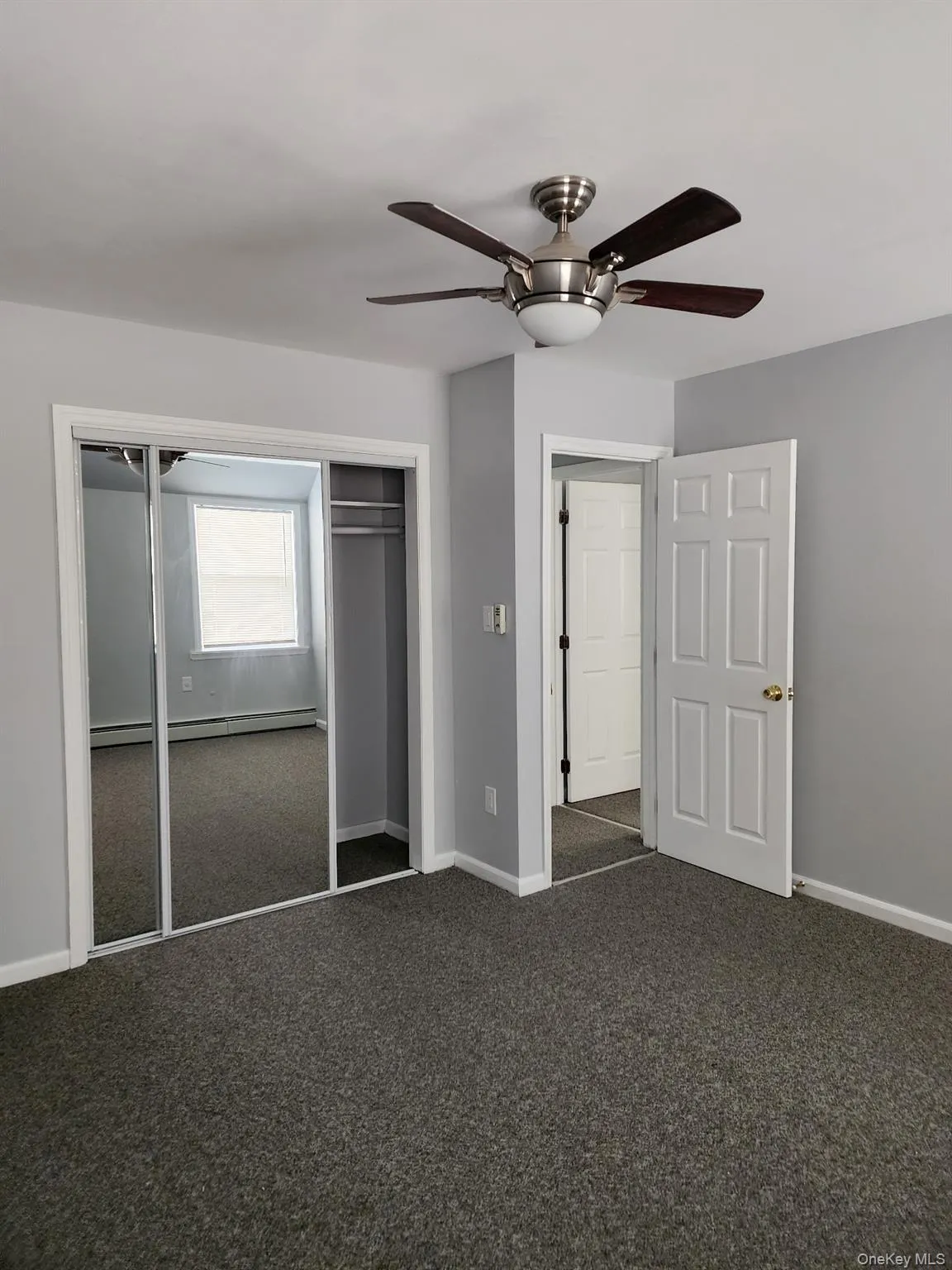 Unfurnished bedroom featuring a closet, carpet floors, ceiling fan, and a baseboard radiator Unfurnished bedroom featuring a closet, carpet floors, ceiling fan, and a baseboard radiator