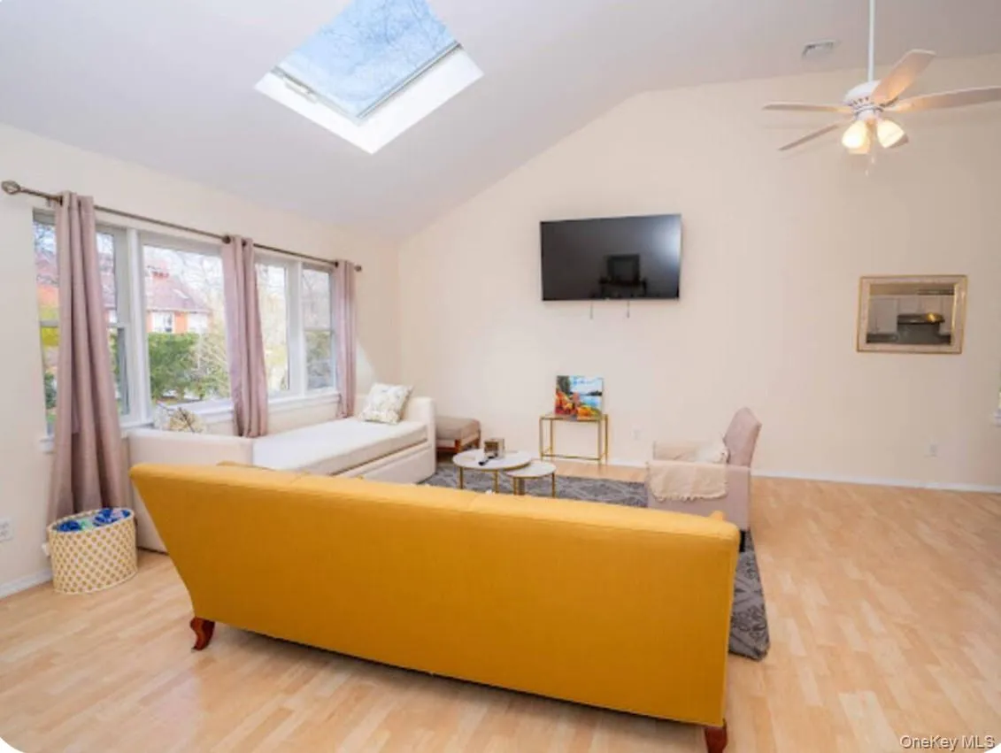 Living area with a skylight, vaulted ceiling, and light wood-type flooring Living area with a skylight, vaulted ceiling, and light wood-type flooring