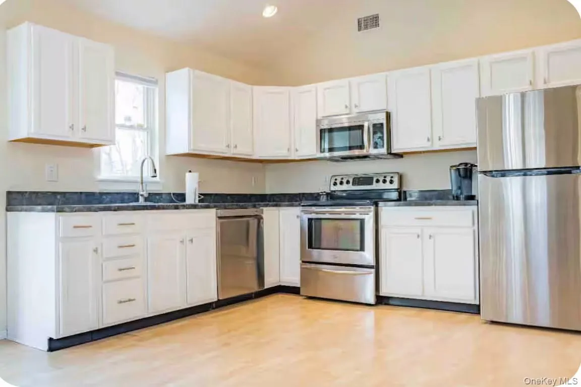 Kitchen featuring appliances with stainless steel finishes, white cabinets, dark countertops, and recessed lighting Kitchen featuring appliances with stainless steel finishes, white cabinets, dark countertops, and recessed lighting