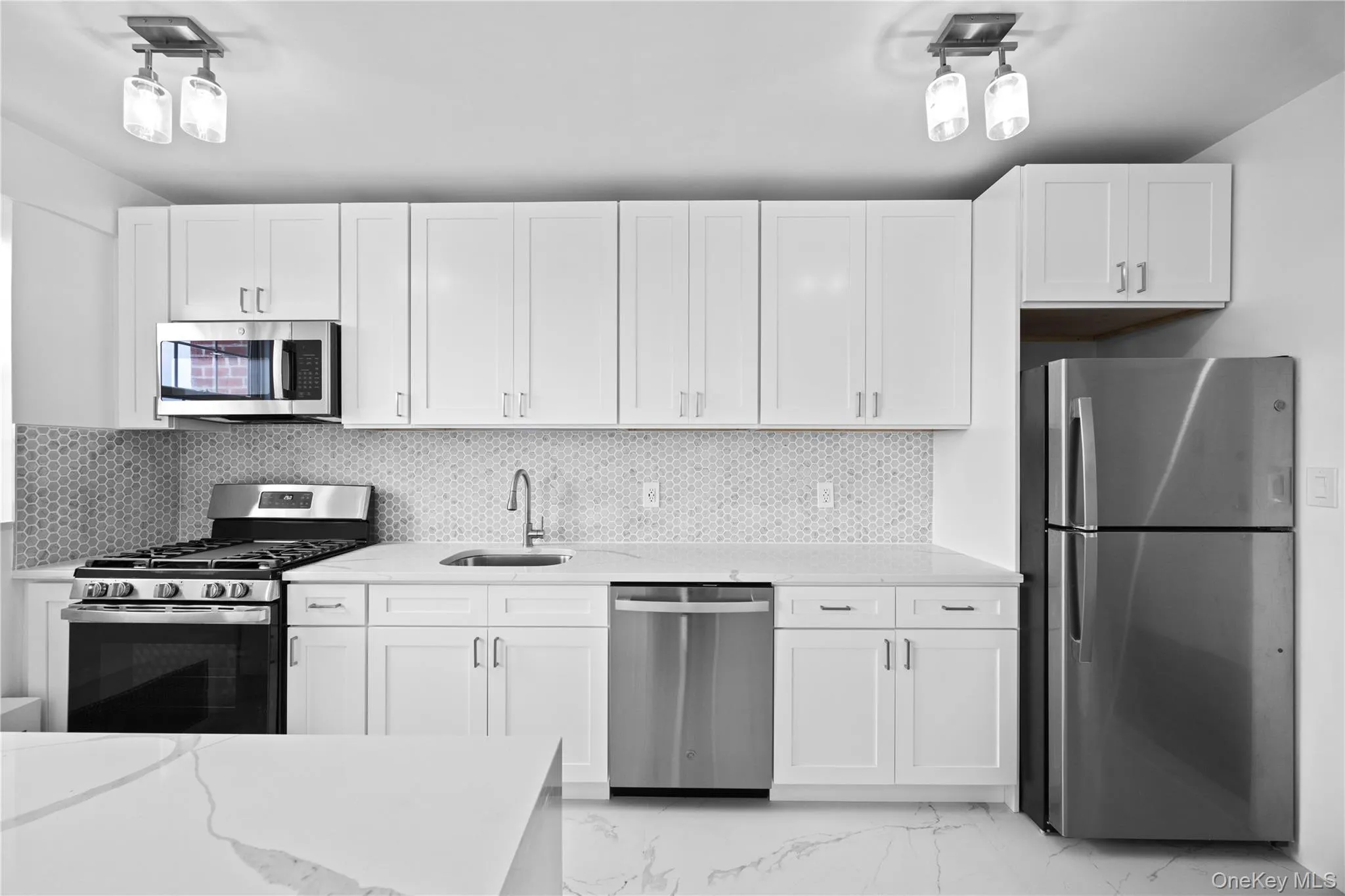 Kitchen with stainless steel appliances, light marble finish floors, white cabinets, light stone countertops, and tasteful backsplash Kitchen with stainless steel appliances, light marble finish floors, white cabinets, light stone countertops, and tasteful backsplash