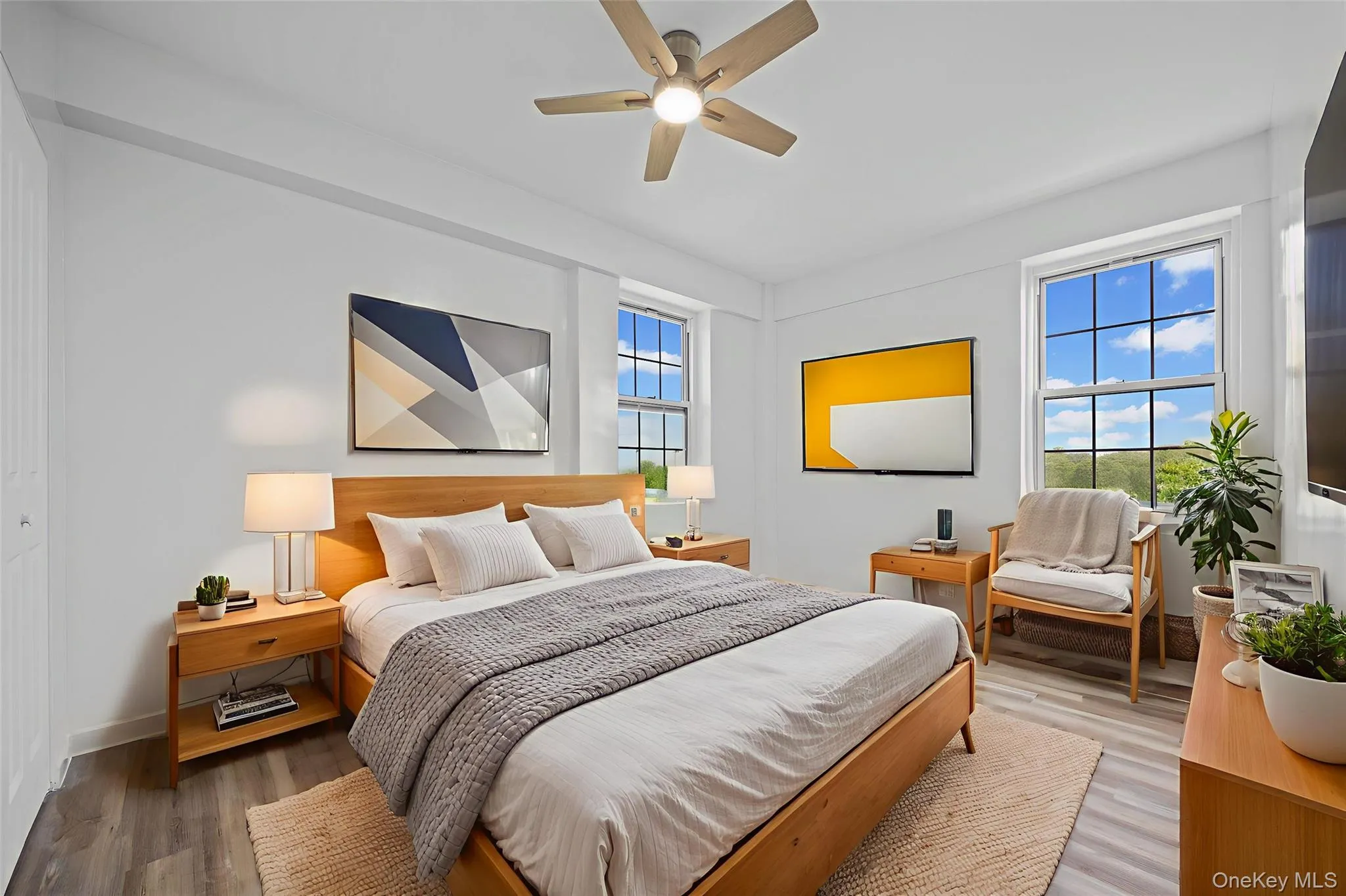 Bedroom with multiple windows, light wood-style floors, and ceiling fan Bedroom with multiple windows, light wood-style floors, and ceiling fan