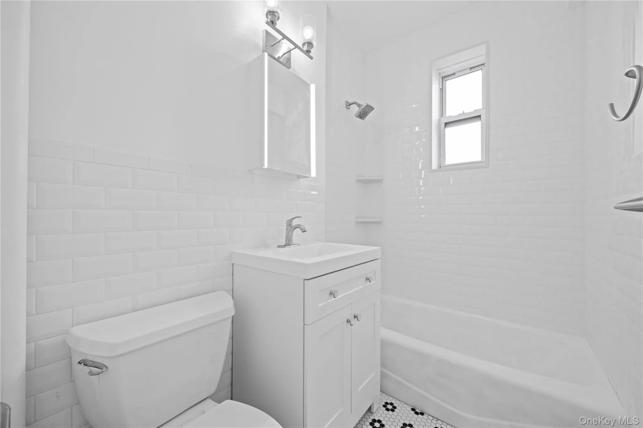 Full bathroom featuring tile walls, vanity, shower / washtub combination, and tile patterned floors Full bathroom featuring tile walls, vanity, shower / washtub combination, and tile patterned floors