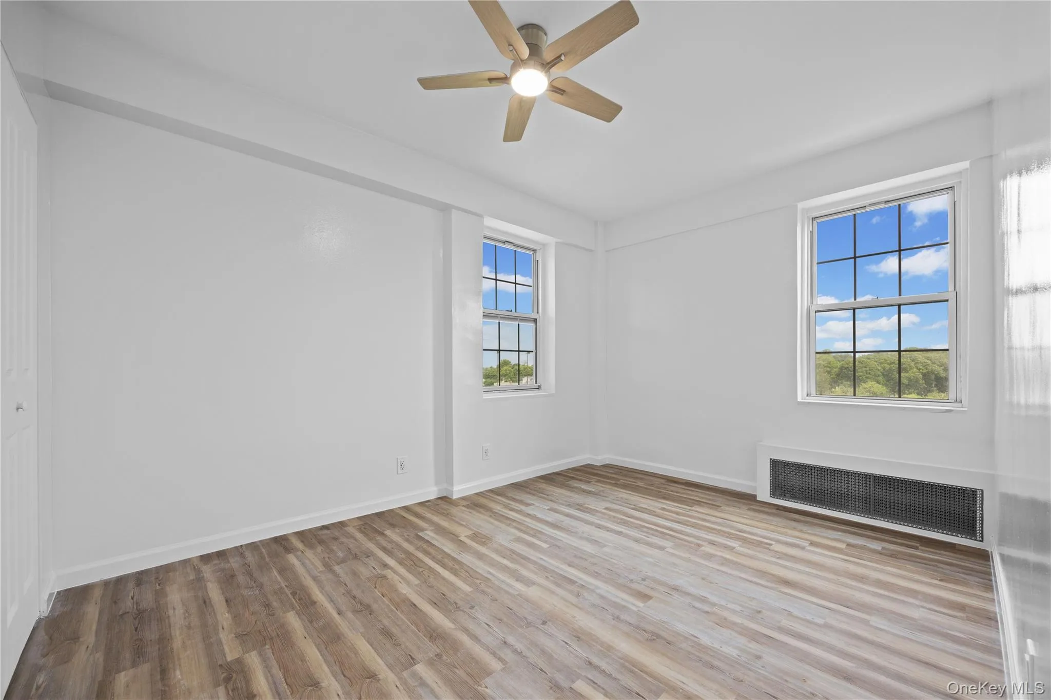 Spare room with radiator, plenty of natural light, wood finished floors, and a ceiling fan Spare room with radiator, plenty of natural light, wood finished floors, and a ceiling fan