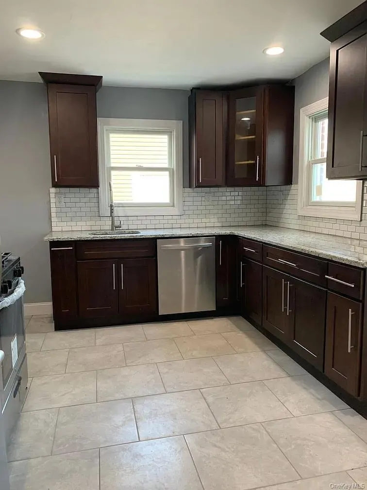 Kitchen with backsplash, light stone countertops, recessed lighting, dishwasher, and glass insert cabinets Kitchen with backsplash, light stone countertops, recessed lighting, dishwasher, and glass insert cabinets