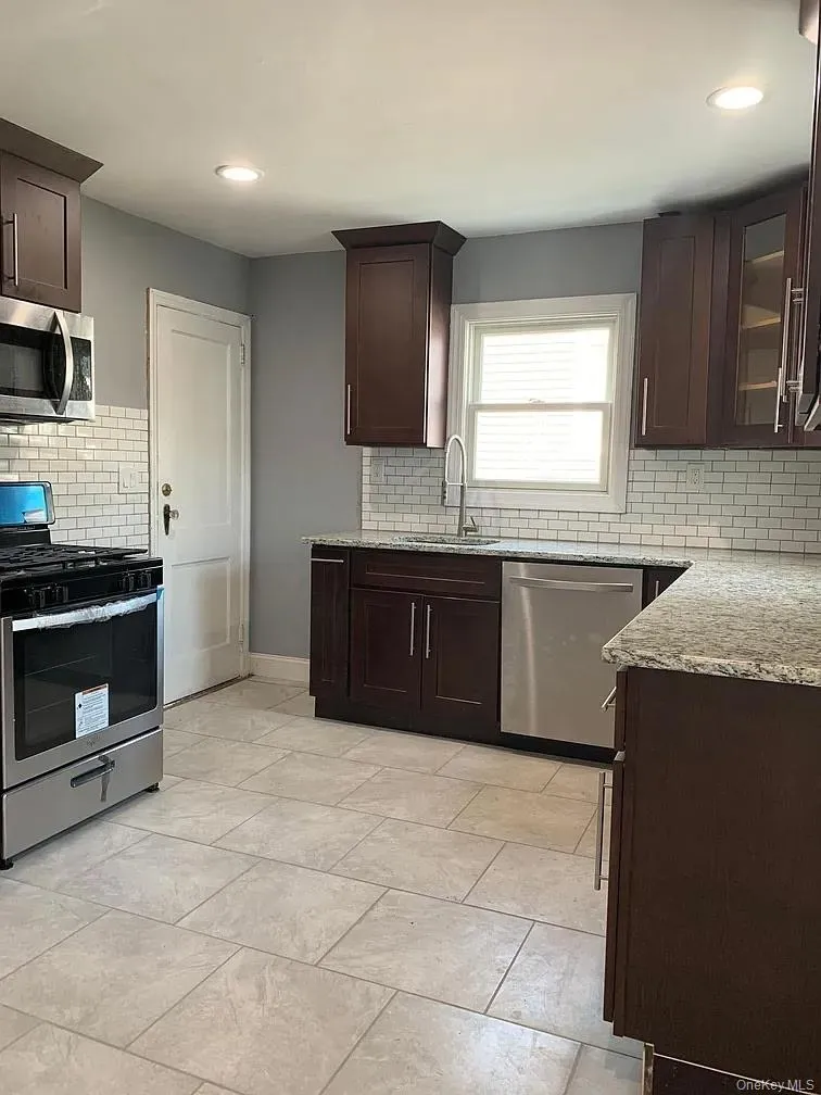 Kitchen featuring dark brown cabinetry, backsplash, appliances with stainless steel finishes, and recessed lighting Kitchen featuring dark brown cabinetry, backsplash, appliances with stainless steel finishes, and recessed lighting