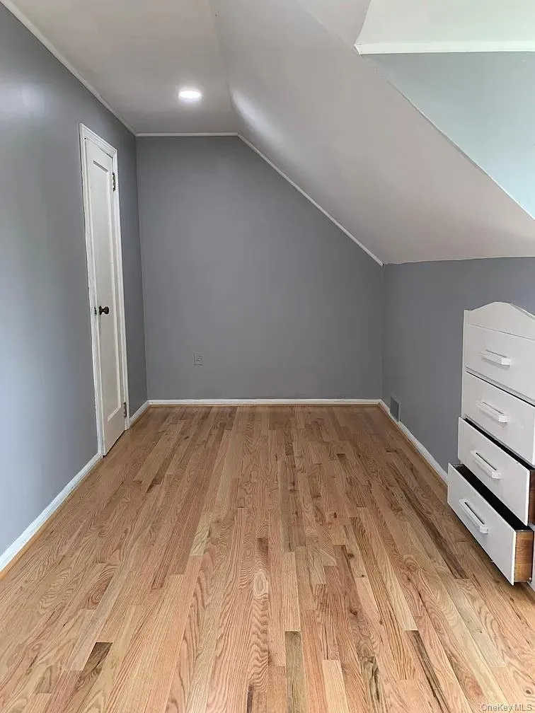 Additional living space with vaulted ceiling and light wood finished floors Additional living space with vaulted ceiling and light wood finished floors