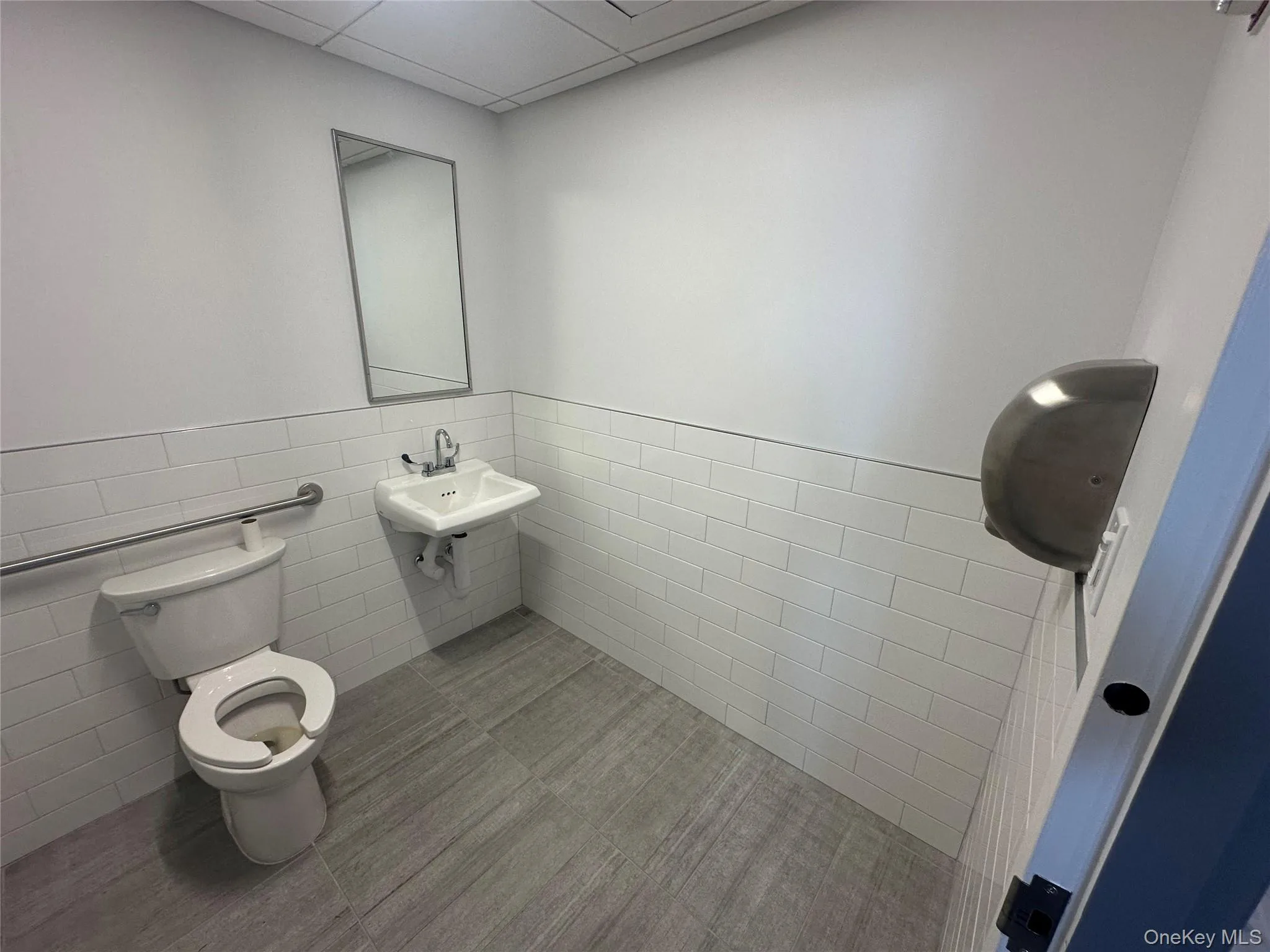 Bathroom featuring tile walls, wainscoting, a paneled ceiling, and tile patterned floors Bathroom featuring tile walls, wainscoting, a paneled ceiling, and tile patterned floors