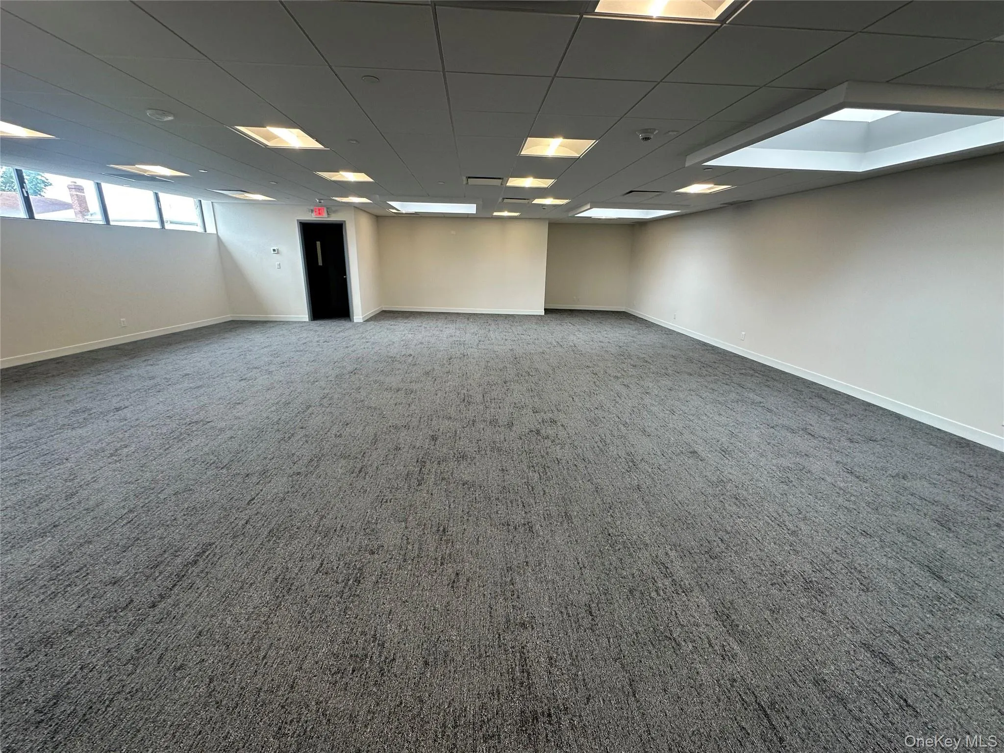 Carpeted empty room with a drop ceiling and baseboards Carpeted empty room with a drop ceiling and baseboards