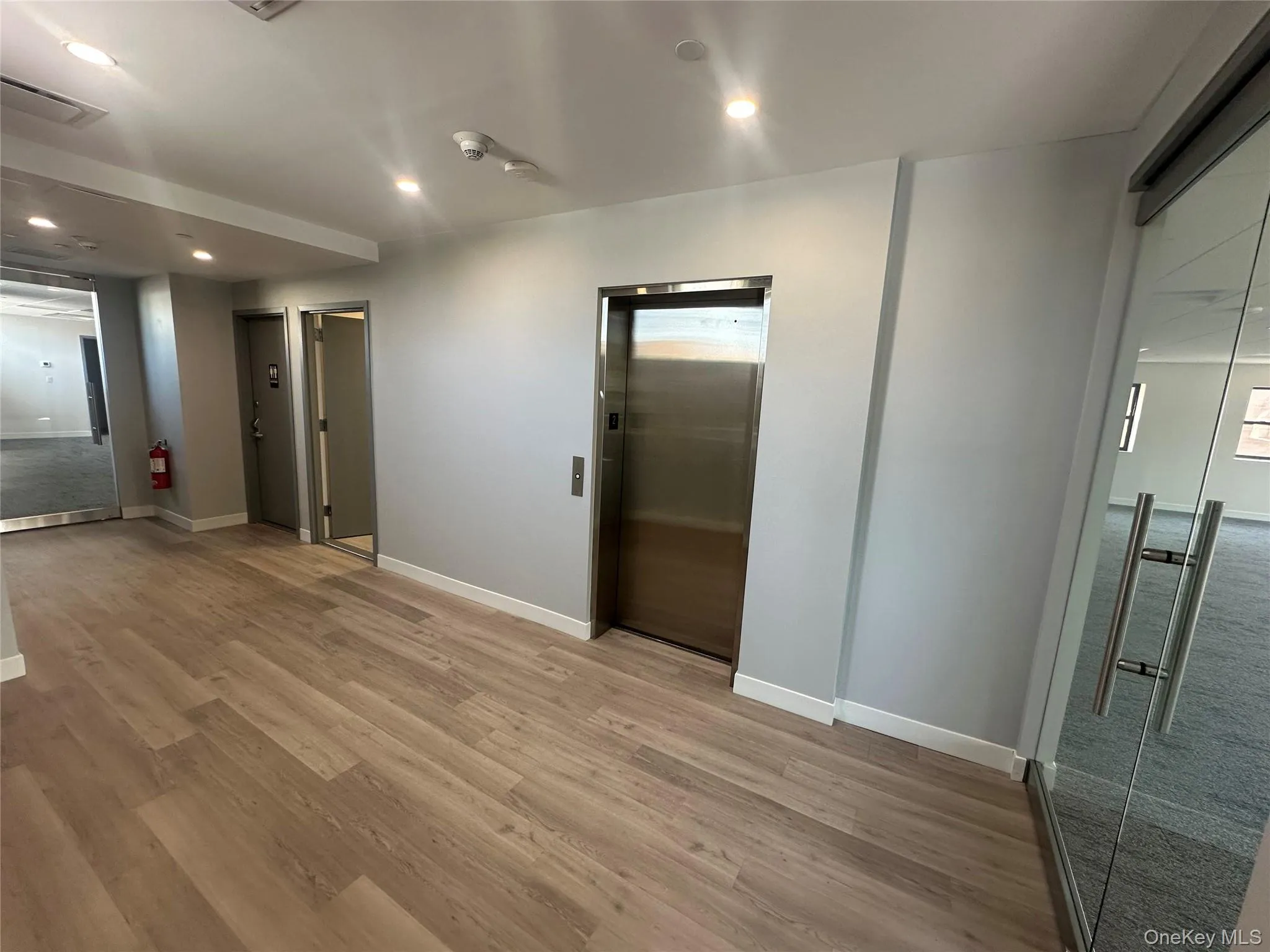 Unfurnished room featuring elevator, recessed lighting, and light wood finished floors Unfurnished room featuring elevator, recessed lighting, and light wood finished floors