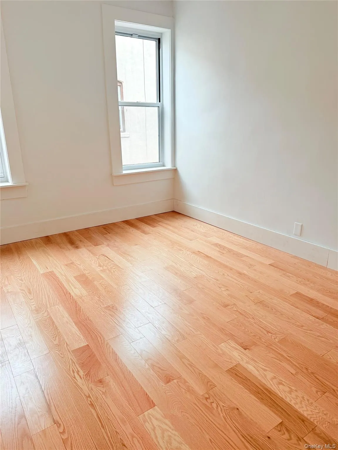 Spare room with baseboards and light wood-type flooring Spare room with baseboards and light wood-type flooring