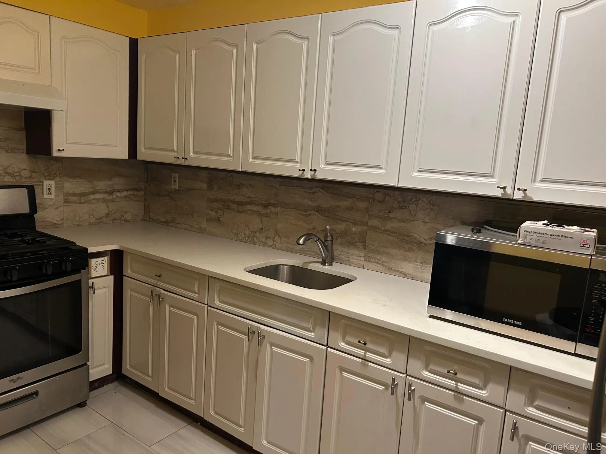 Kitchen featuring stainless steel appliances, white cabinets, light stone counters, and under cabinet range hood Kitchen featuring stainless steel appliances, white cabinets, light stone counters, and under cabinet range hood
