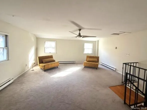 Unfurnished room with baseboard heating, carpet, and an upstairs landing Unfurnished room with baseboard heating, carpet, and an upstairs landing