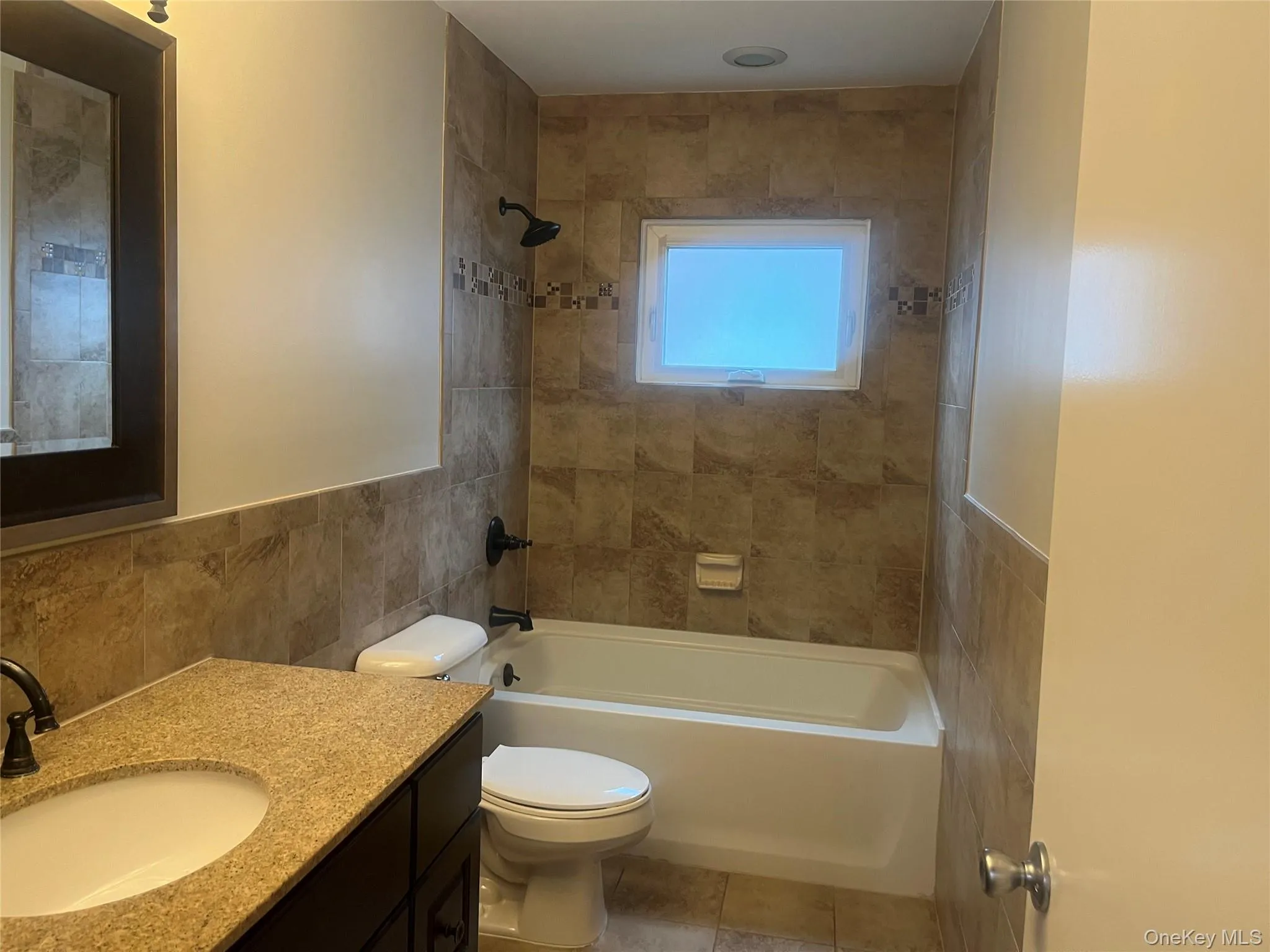 Full Bathroom featuring vanity, tile walls, washtub / shower combination, light tile flooring Full Bathroom featuring vanity, tile walls, washtub / shower combination, light tile flooring