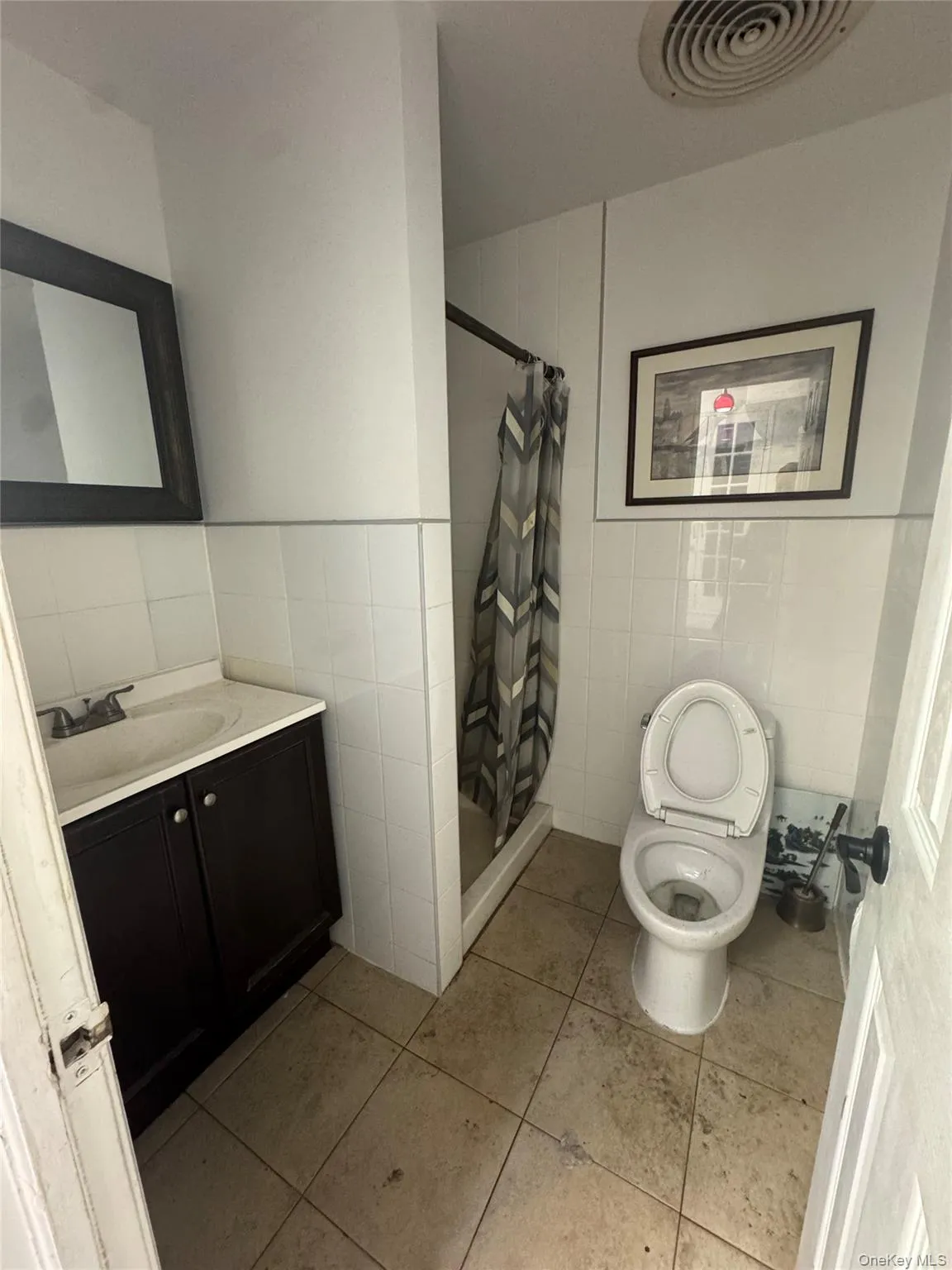 Bathroom with tile walls, vanity, a shower stall, and light tile patterned flooring Bathroom with tile walls, vanity, a shower stall, and light tile patterned flooring