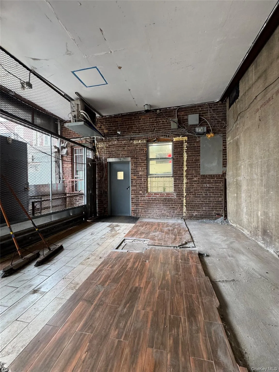 Spare room featuring hardwood / wood-style floors and brick wall Spare room featuring hardwood / wood-style floors and brick wall